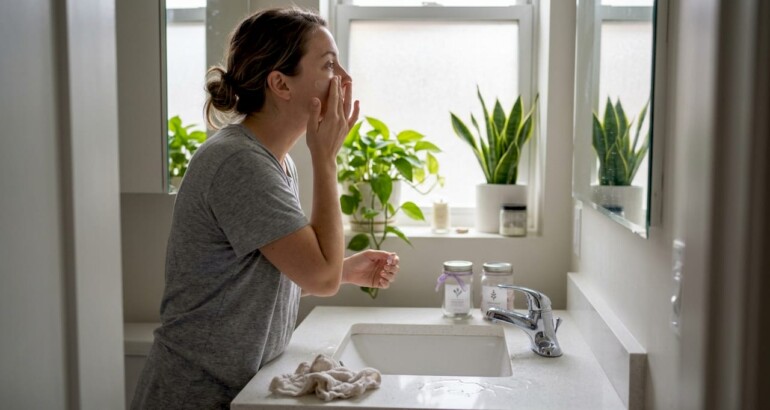 Woman using vegan skincare in home bathroom