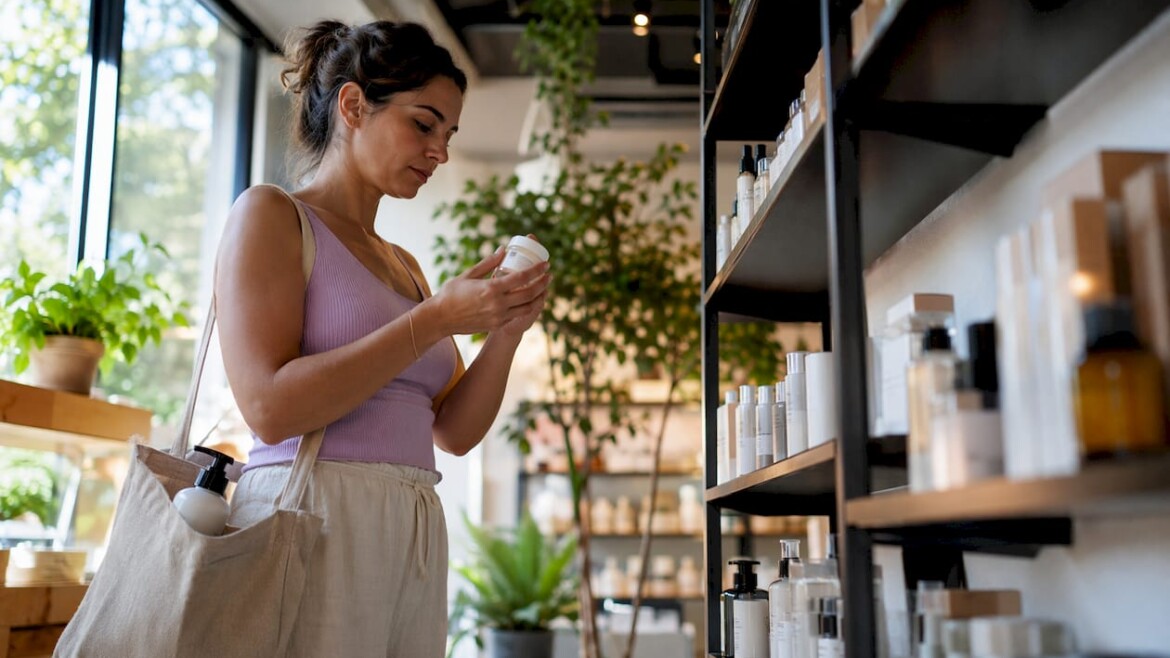 Woman reading skincare ingredient labels in pharmacy aisle