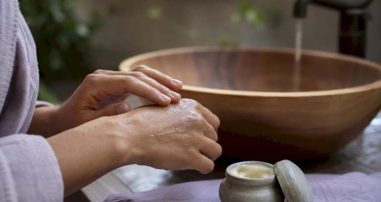 Hands applying balm to dry skin after washing