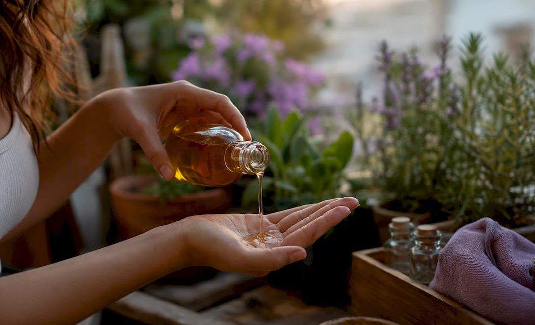 Hands pouring warm carrier oil for massage
