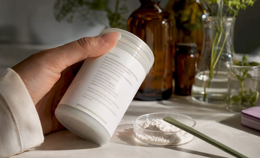 Hand inspecting an anonymous skincare ingredient label